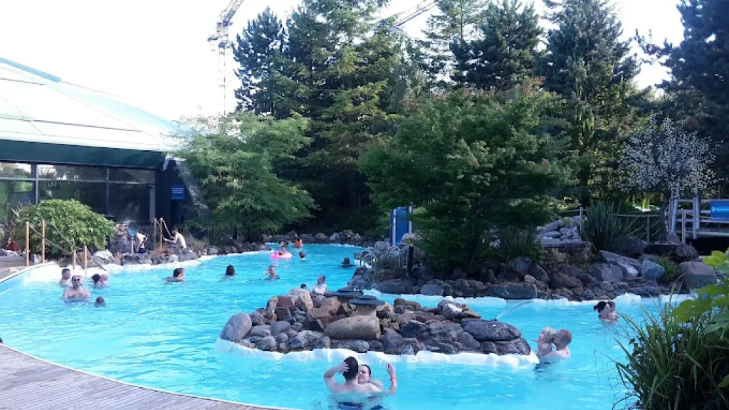 Guests enjoying the outdoor heated pool at Center Parcs Longleat, with children on inflatables and forest scenery in the background.