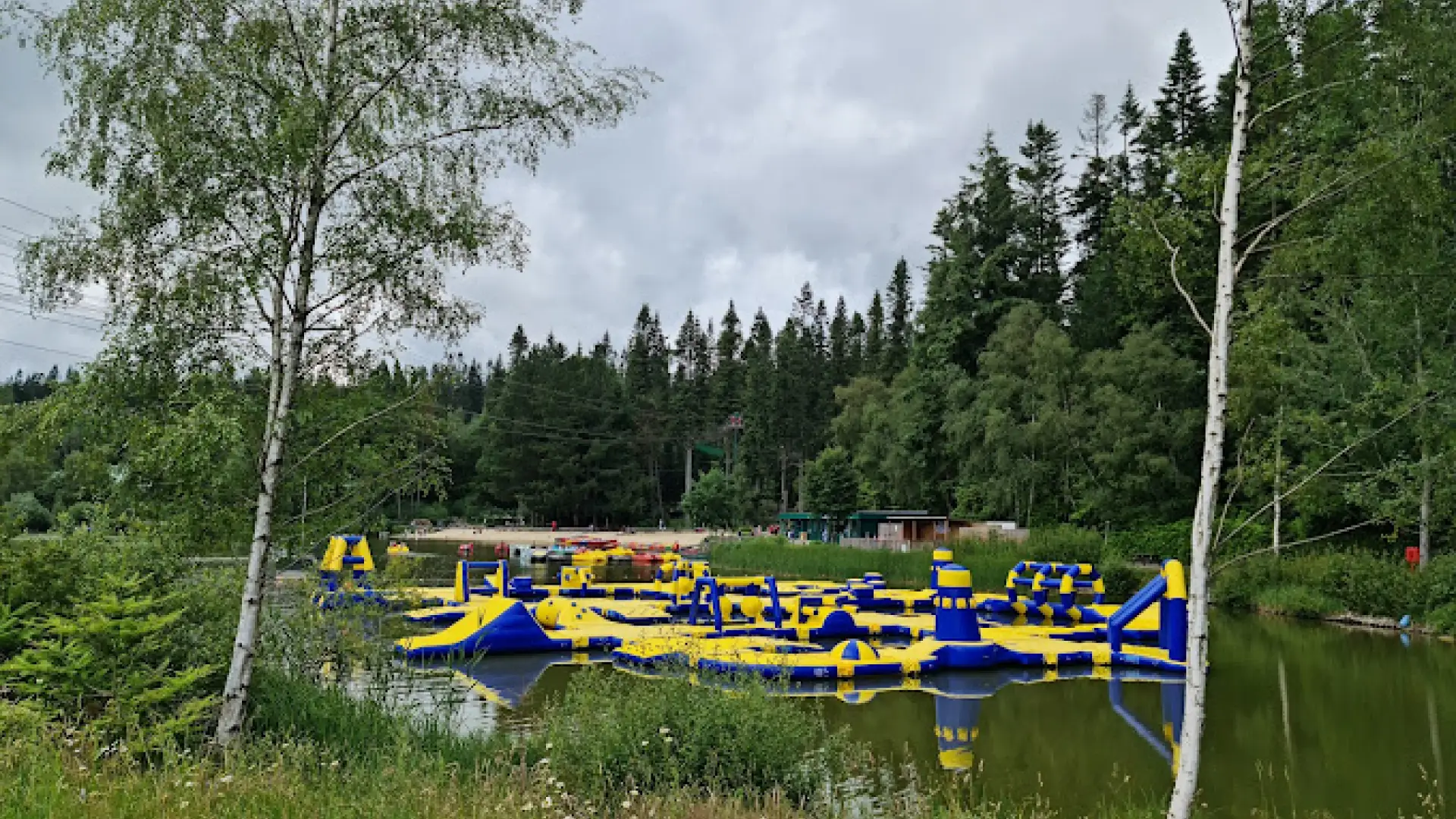Giant inflatable Aqua Parc floating on the lake at Center Parcs Longleat, with colourful slides and climbing areas surrounded by lush woodland.