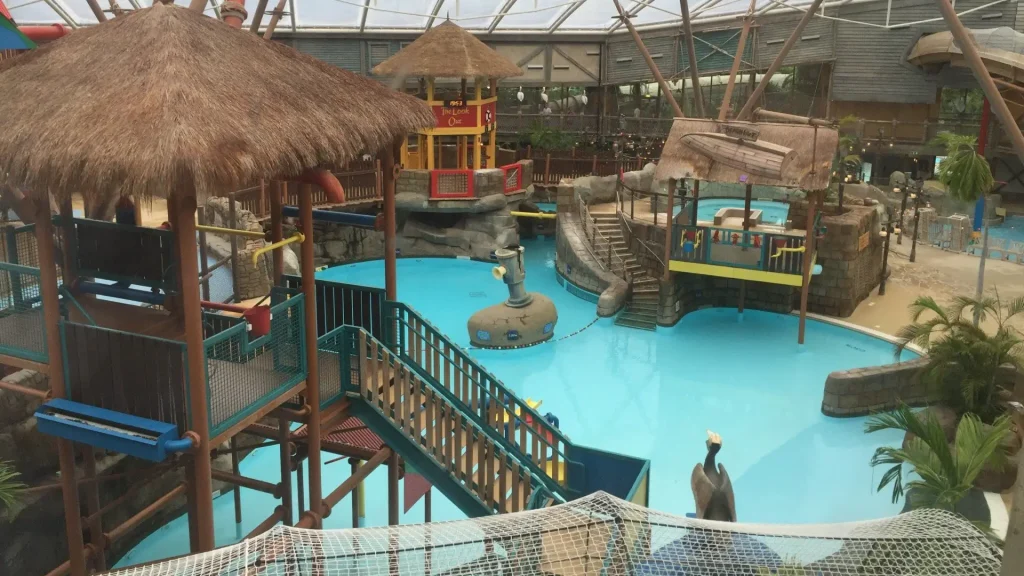 Indoor view of Alton Towers Water Park featuring pools, water slides, and play structures with a tropical island theme