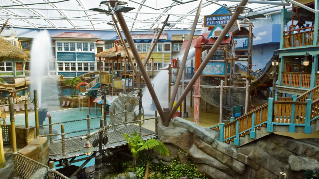 Water features and themed play structures at Alton Towers Water Park, including Paradise Plumbers, fountains, and wooden walkways in a tropical setting