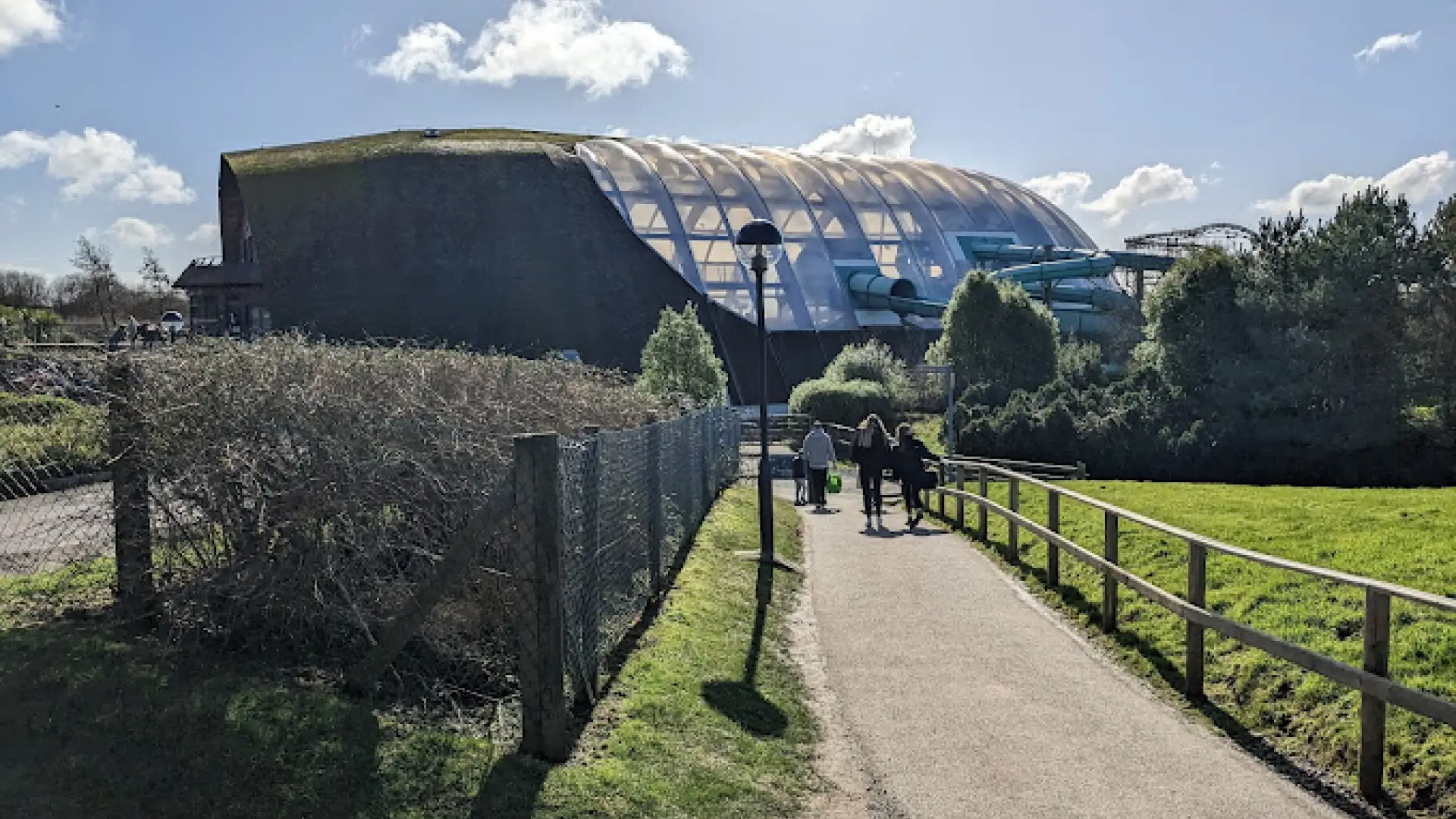 Pathway leading to the Blue Lagoon Water Park at Bluestone, showing the dome-shaped glass roof and water slides nestled in the scenic Pembrokeshire landscape.