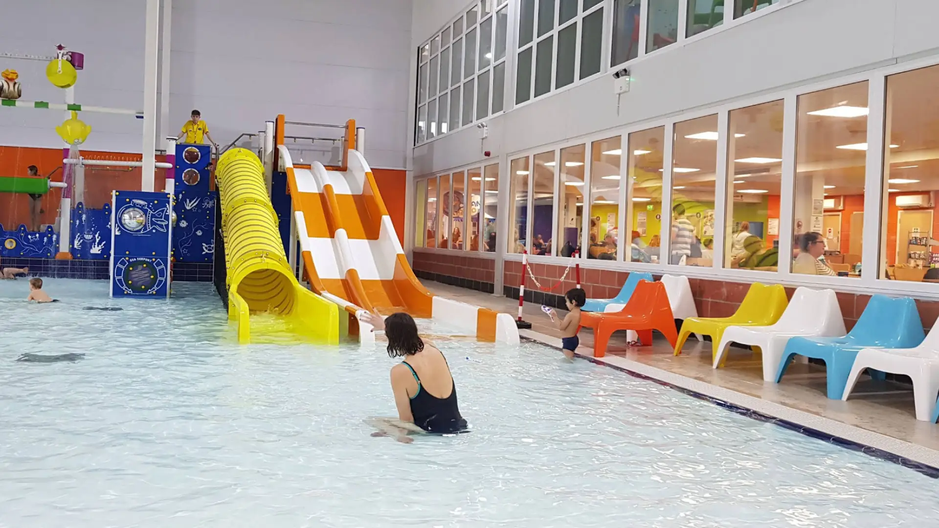 Children playing in the indoor splash pool with colourful slides and family seating at Brean Splash Waterpark Somerset.