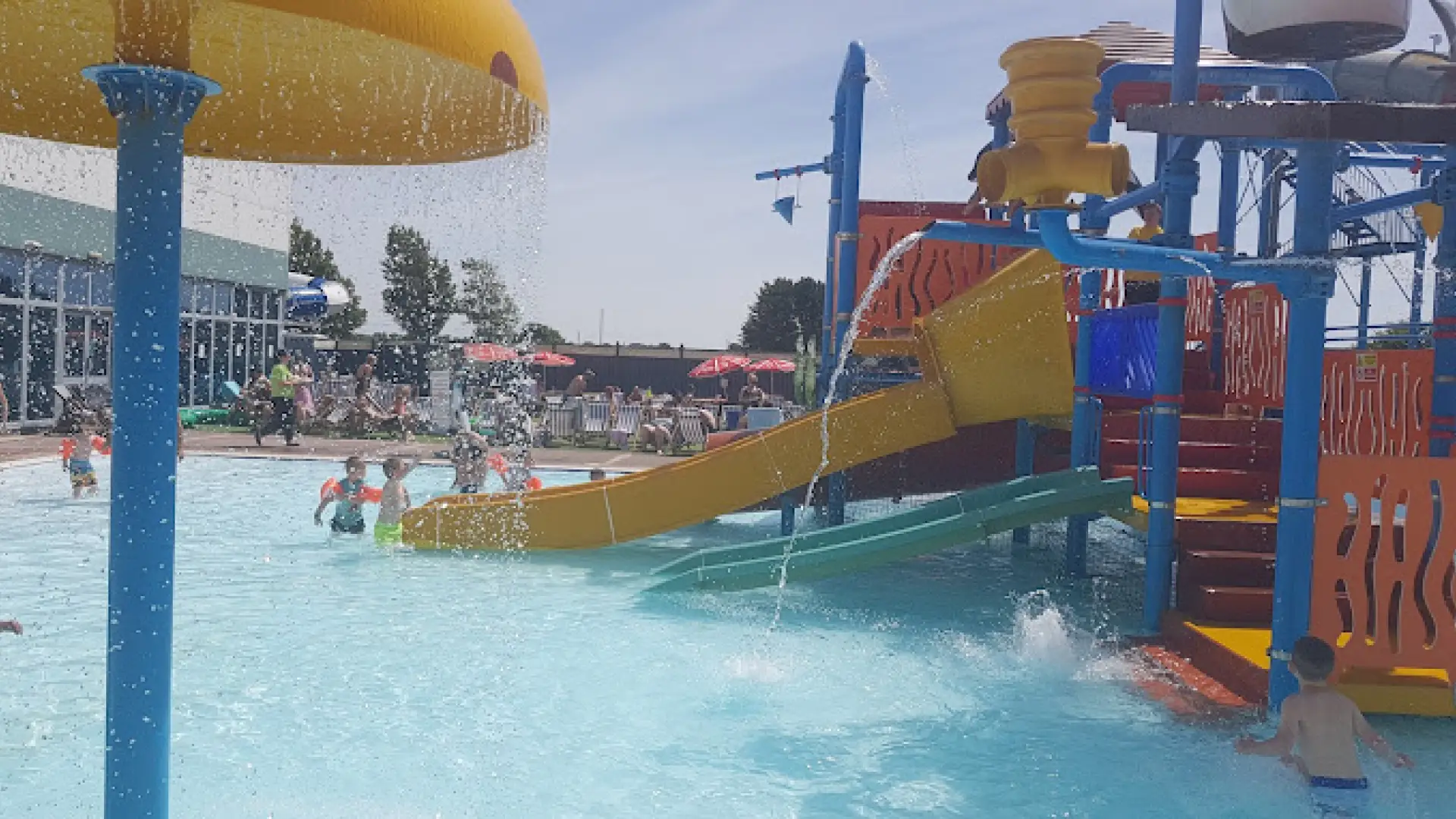 Children playing with water features, tipping buckets, and slides at the outdoor splash area of Brean Splash Waterpark Somerset.