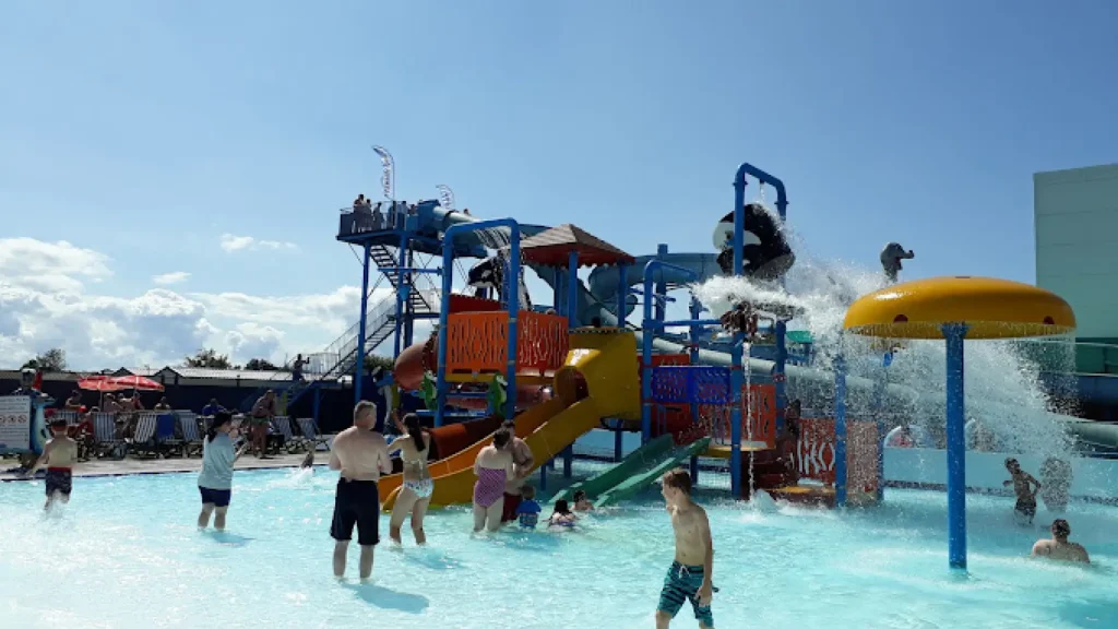 Families playing in the outdoor splash park with water slides, tipping buckets, and spray features at Brean Splash Waterpark Somerset.