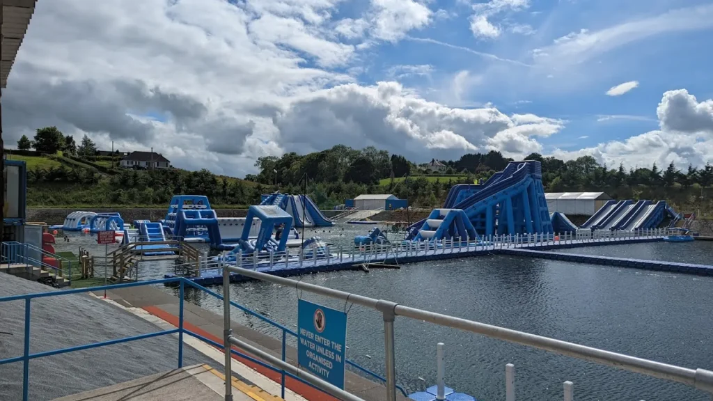 Wide-angle view of inflatable water slides and floating obstacle course at Let's Go Hydro aqua park in Northern Ireland on a partly cloudy day.