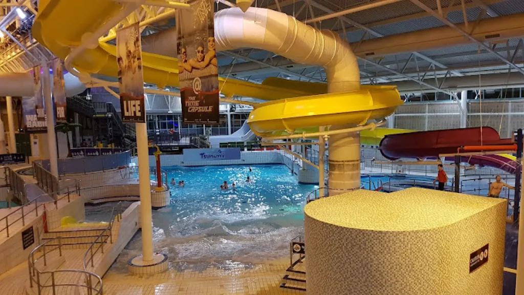 Evening view of Tsunami wave pool under yellow slide at The Time Capsule Water Park Scotland, purple flume in background.