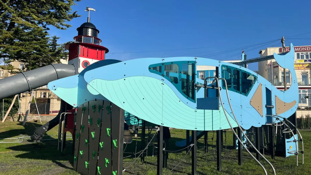 Whale-themed climbing structure at the Water Adventure Play Park in Weston-super-Mare Play Park with slide and climbing wall under blue sky.