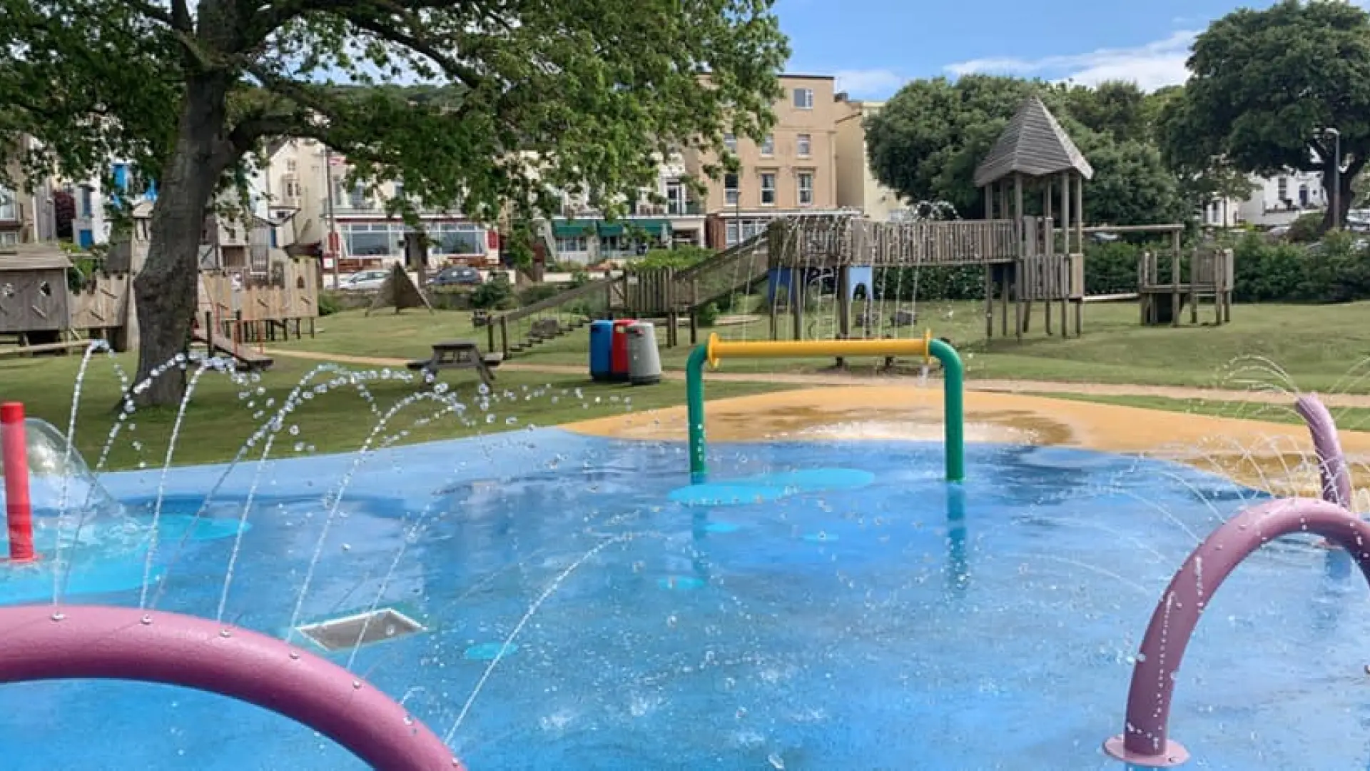 Colourful splash pad with water arches and wooden climbing structures at Water Adventure Play Park in Weston-super-Mare.