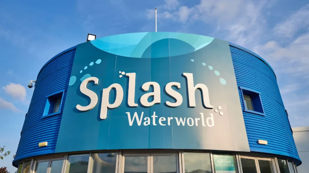 Blue circular building with large Splash Waterworld sign at Butlins Minehead resort under a partly cloudy sky.