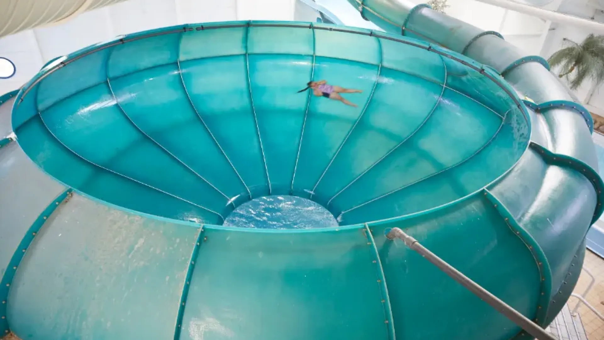 Person spinning inside the Space Bowl slide at Butlins Splash Waterworld Minehead water park, moments before splashing into the pool below.