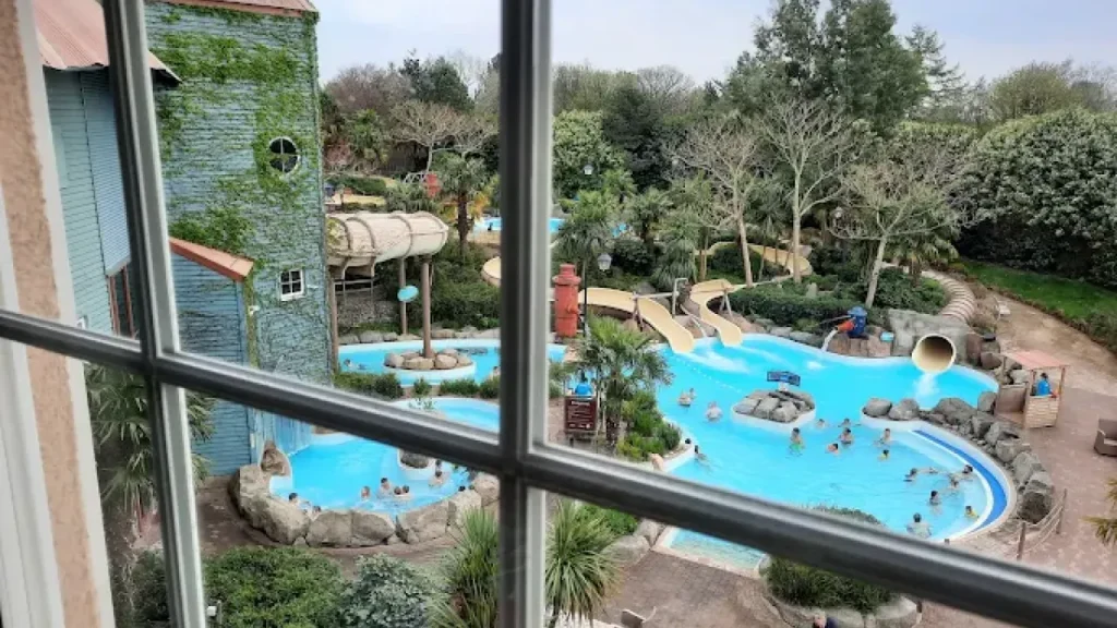 Aerial view of Alton Towers Waterpark with pools, water slides, and swimmers seen through a hotel room window — one of the top-rated places to stay near Alton Towers.