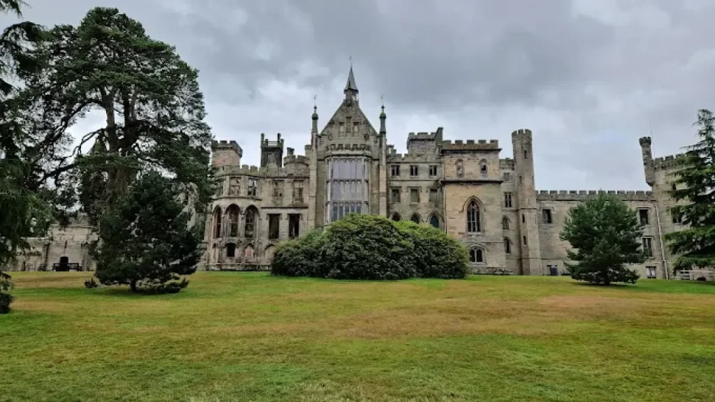 Historic castle building at Alton Towers Resort in Staffordshire, surrounded by trees and green lawn on a cloudy day