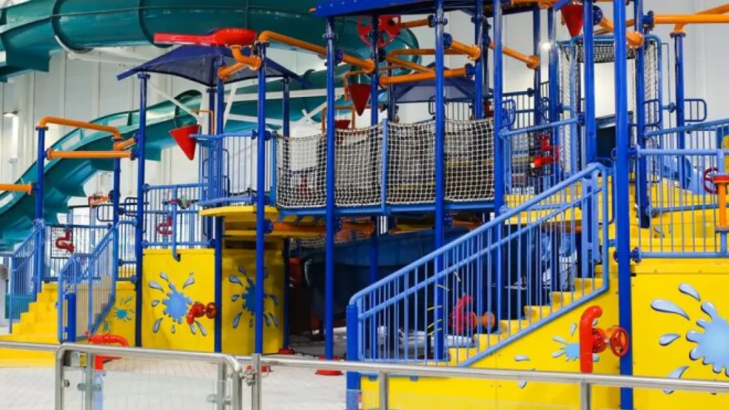 Brightly coloured children’s aqua play structure at Andersonstown Leisure Centre with splash features, stairs, and water cannons.