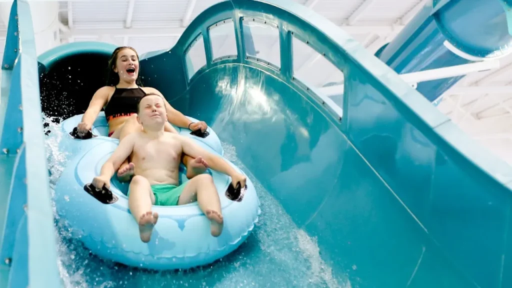 Two riders on a blue inflatable raft enjoying a fast turn on Andersonstown Leisure Centre’s enclosed tube water slide.