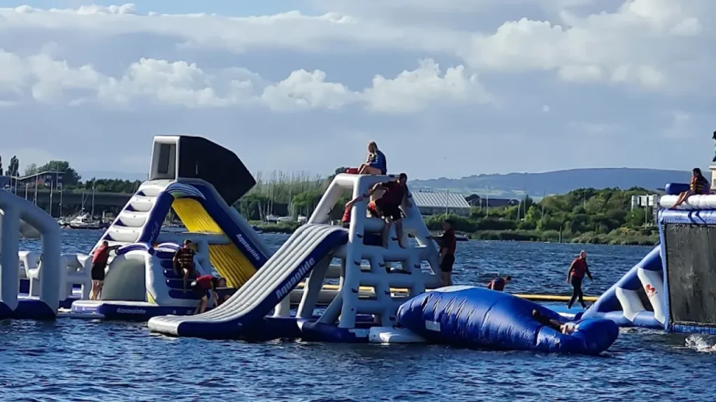 Children and adults enjoying inflatable slides and climbing walls at Aqua Park Cardiff.