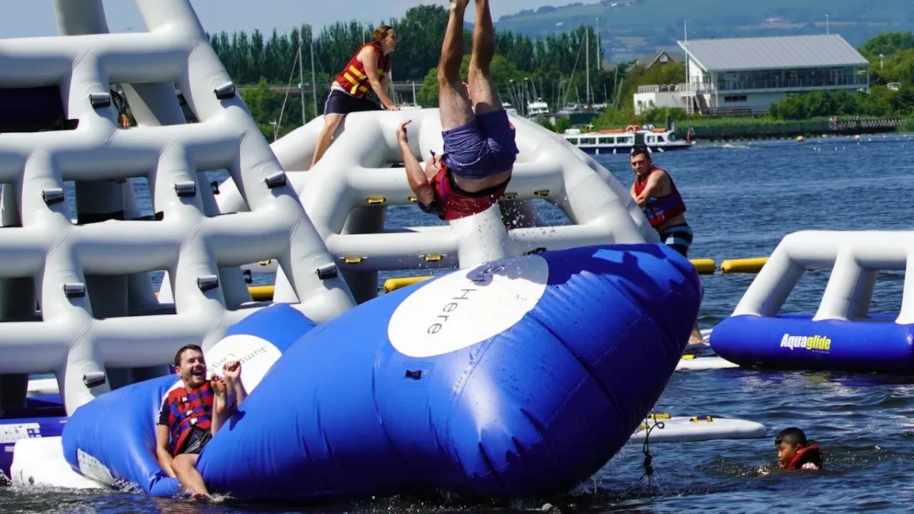 Man flipping backwards from inflatable launcher into the lake at Aqua Park Cardiff.