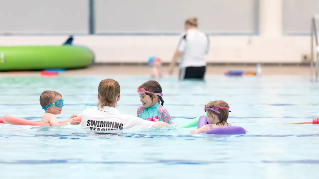 Swimming instructor teaching young children in a pool at Bangor Aurora Leisure Centre swim lessons.