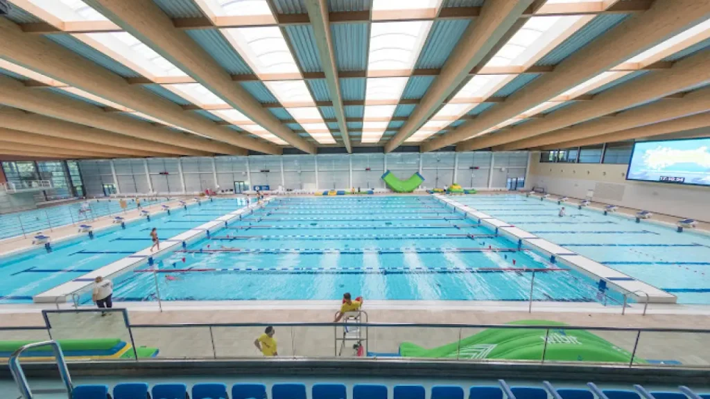 Wide view of Bangor Aurora Leisure Centre 50-metre Olympic pool with swim lanes, lifeguards, and spectator seating.