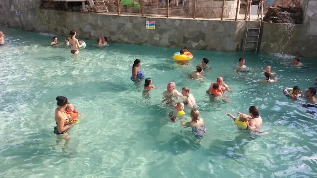 Parents and children swimming and playing in the shallow family pool at Center Parcs Woburn Forest indoor water park.