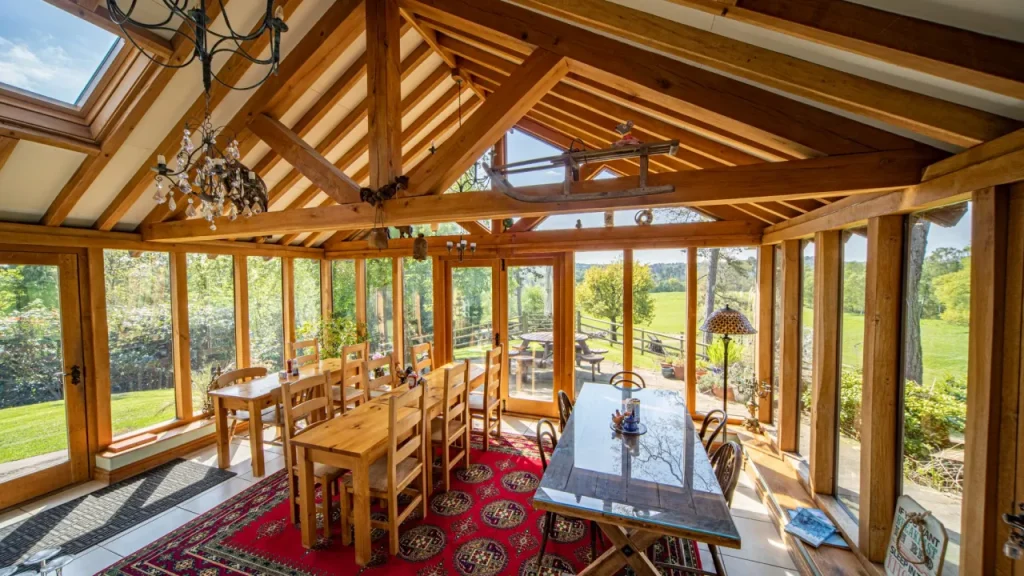 Bright conservatory dining area with wooden beams and countryside views at Chained Oak Farm B&B near Alton Towers.
