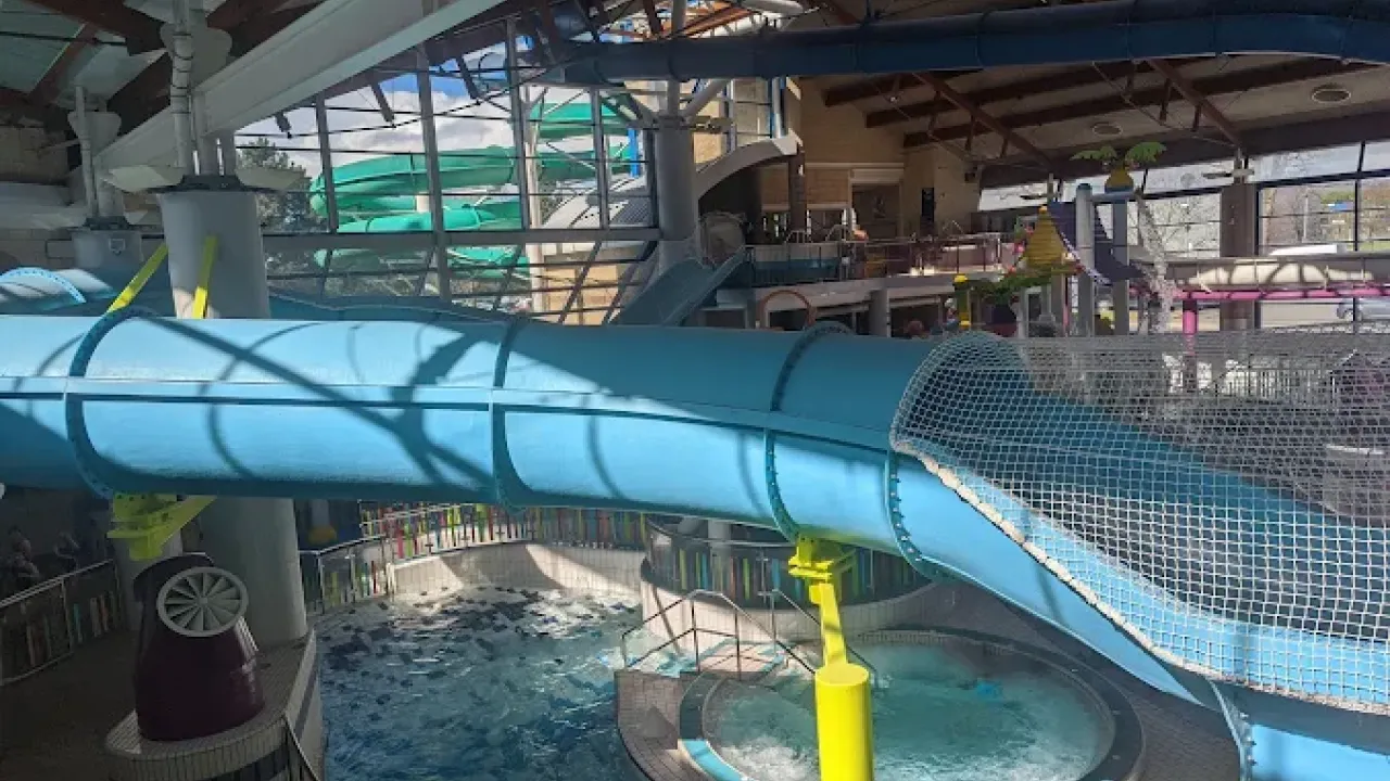 Interior view of a large enclosed blue water slide at Lagan Valley LeisurePlex leading into a splash pool with natural light and viewing areas.