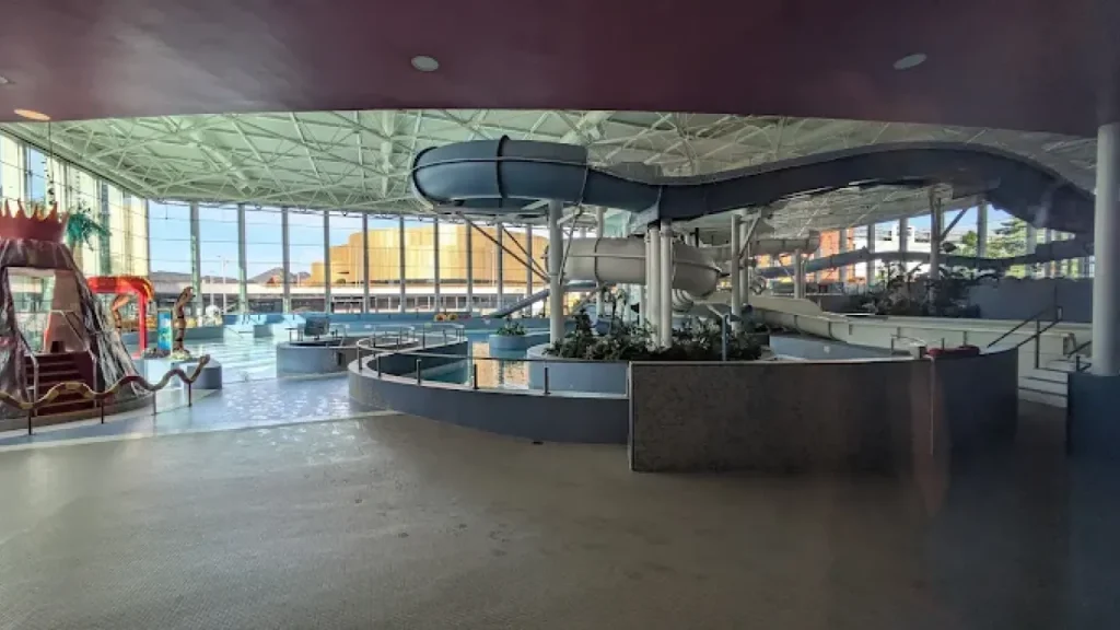 Indoor waterpark at The LC Swansea showcasing winding slides, a volcano play structure, splash zones, and bright natural light from large windows.