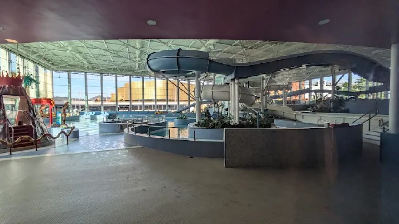 Indoor waterpark at The LC Swansea showcasing winding slides, a volcano play structure, splash zones, and bright natural light from large windows.