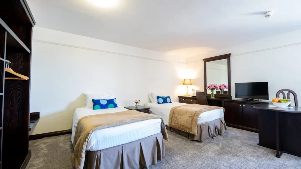 Twin room with two beds, TV, dark wood furniture, and neutral décor at the Marine Court Hotel Bangor Northern Ireland