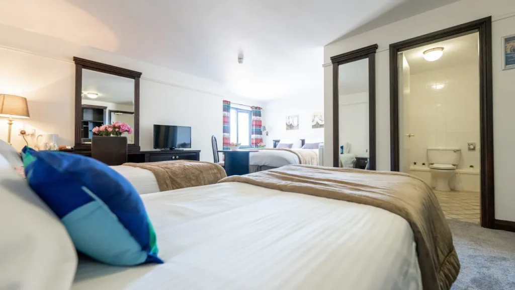 Family room with multiple beds, TV, en-suite bathroom, and natural light at Marine Court Hotel Bangor Northern Ireland
