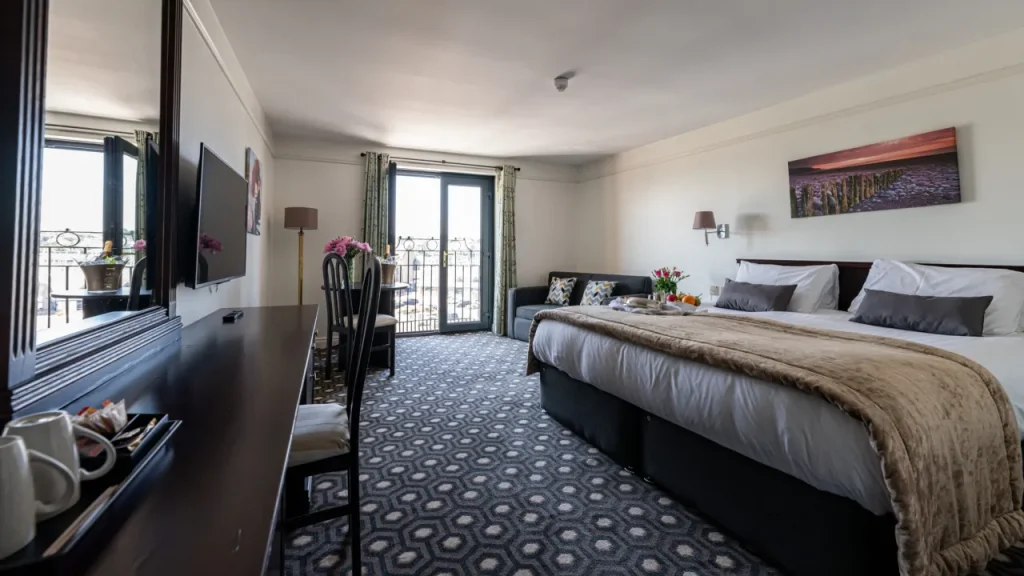 Spacious king room with Juliet balcony, sea view, modern decor, and cosy bedding at Marine Court Hotel Bangor Northern Ireland