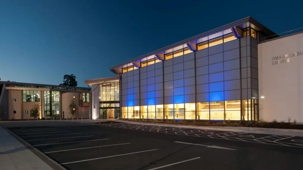 Omagh Leisure Complex at night with blue lighting and modern glass-fronted exterior in Northern Ireland.