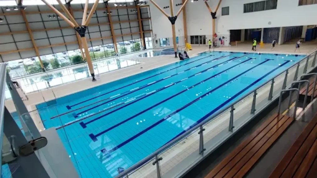 Omagh Leisure Complex 25-metre lane pool with blue water, lifeguards, and wooden spectator seating area.