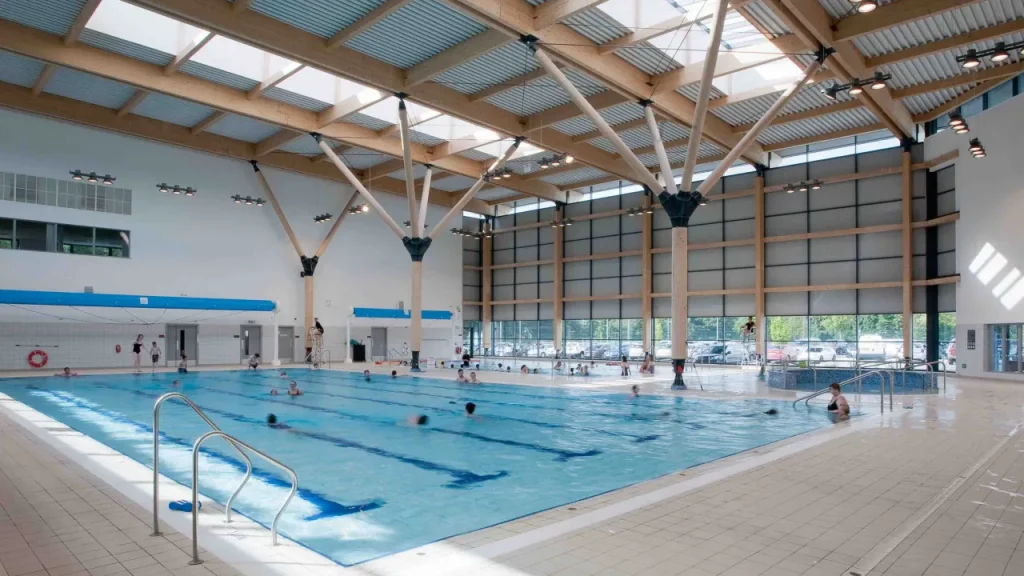 Omagh Leisure Complex indoor pool with swimmers using lane lines in a well-lit modern facility with timber beam ceiling.