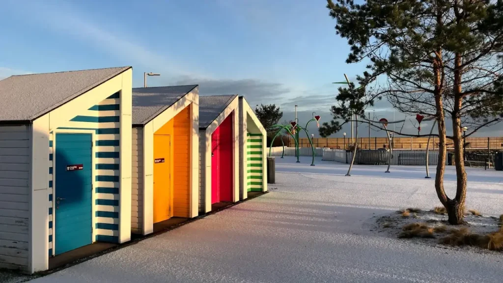 Pickie Funpark colourful beach huts and splash pad area covered in frost on a winter morning in Bangor, Northern Ireland.