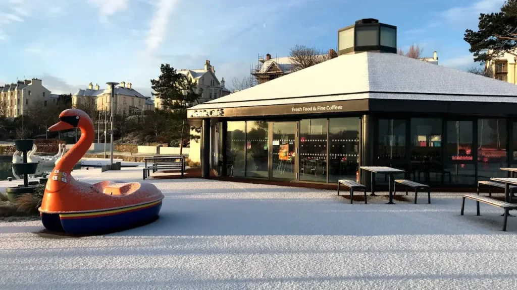 Pickie Café with outdoor seating and an orange swan boat at Pickie Funpark on a frosty winter morning in Bangor, Northern Ireland.