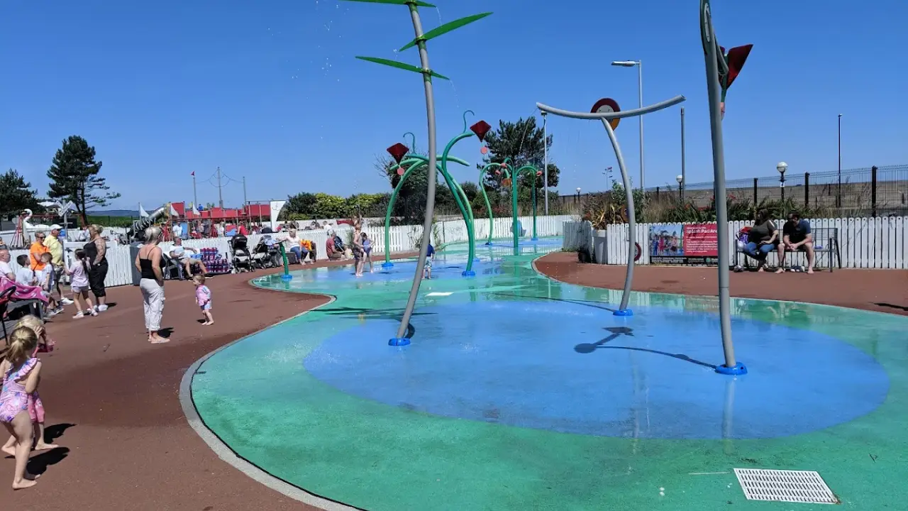 Children playing and families relaxing at Pickie Funpark’s splash pad on a sunny day in Bangor, Northern Ireland.