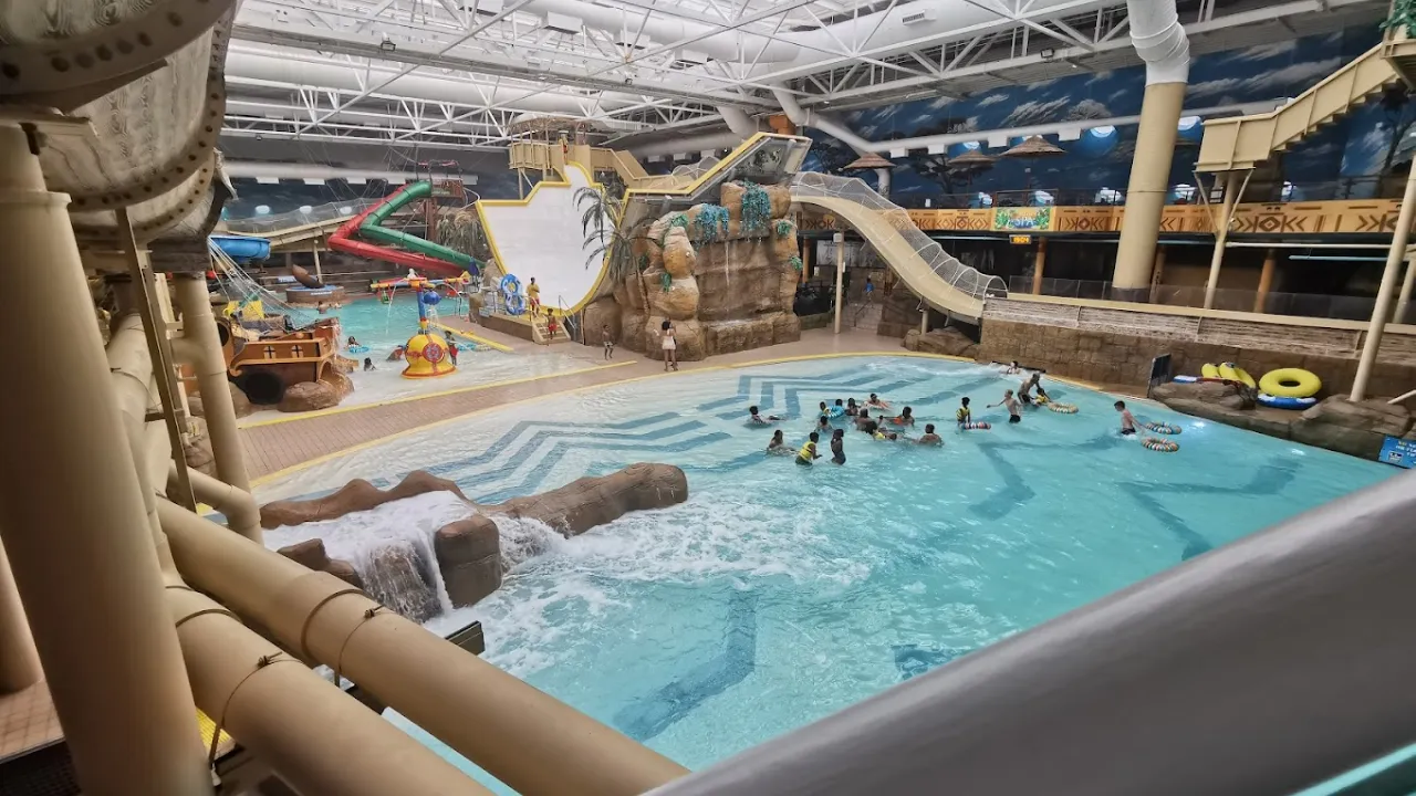 Indoor wave pool and splash play area at Sandcastle Waterpark Blackpool with slides, waterfalls, and guests enjoying the water.