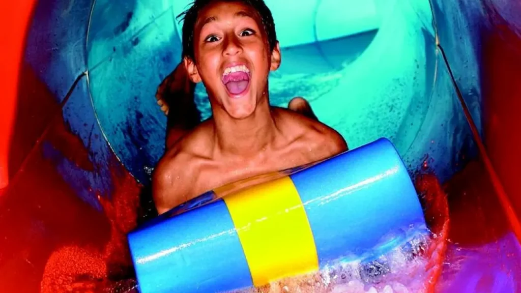 Excited boy riding a colourful mat inside a high-speed water slide at Sandcastle Waterpark Blackpool.