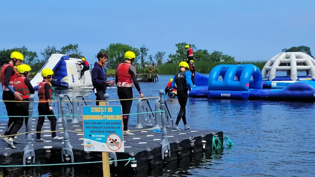 Visitors wearing life jackets and helmets get ready to enter the inflatable water obstacle course at Sblash Aqua Park.