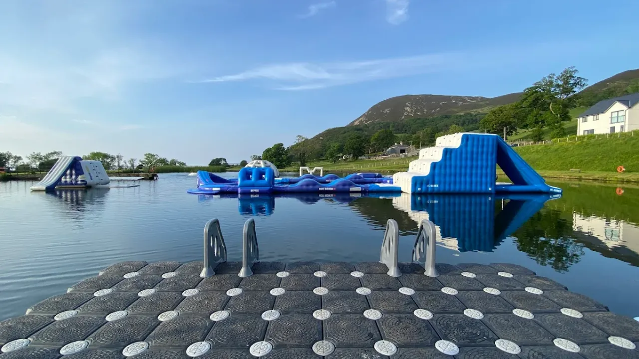 Floating inflatable water park seen from dockside, featuring slides and climbing obstacles at Sblash Aqua Park.
