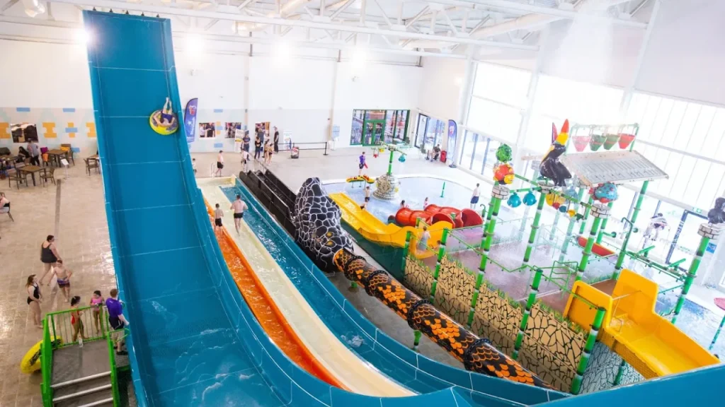 Indoor shot from the top of SC2 Rhyl waterpark featuring the Boomerang tube slide, multi-lane racing slides, and colourful aquatic play areas.