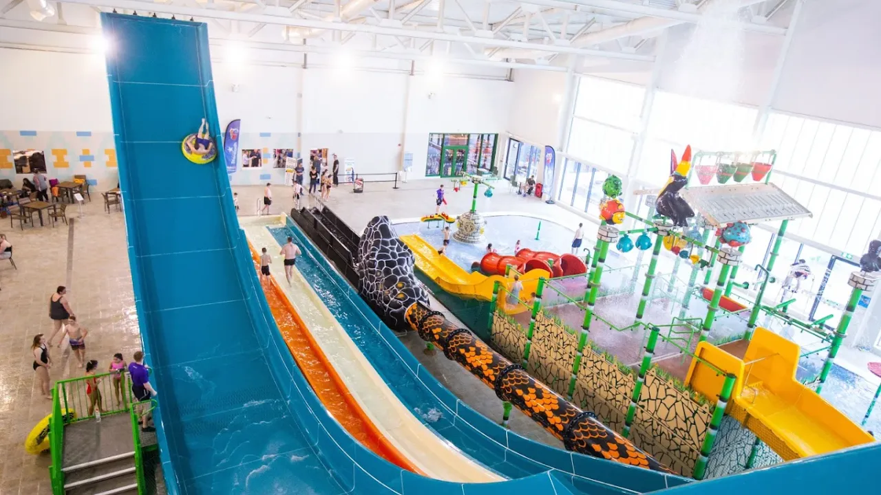 Indoor shot from the top of SC2 Rhyl waterpark featuring the Boomerang tube slide, multi-lane racing slides, and colourful aquatic play areas.