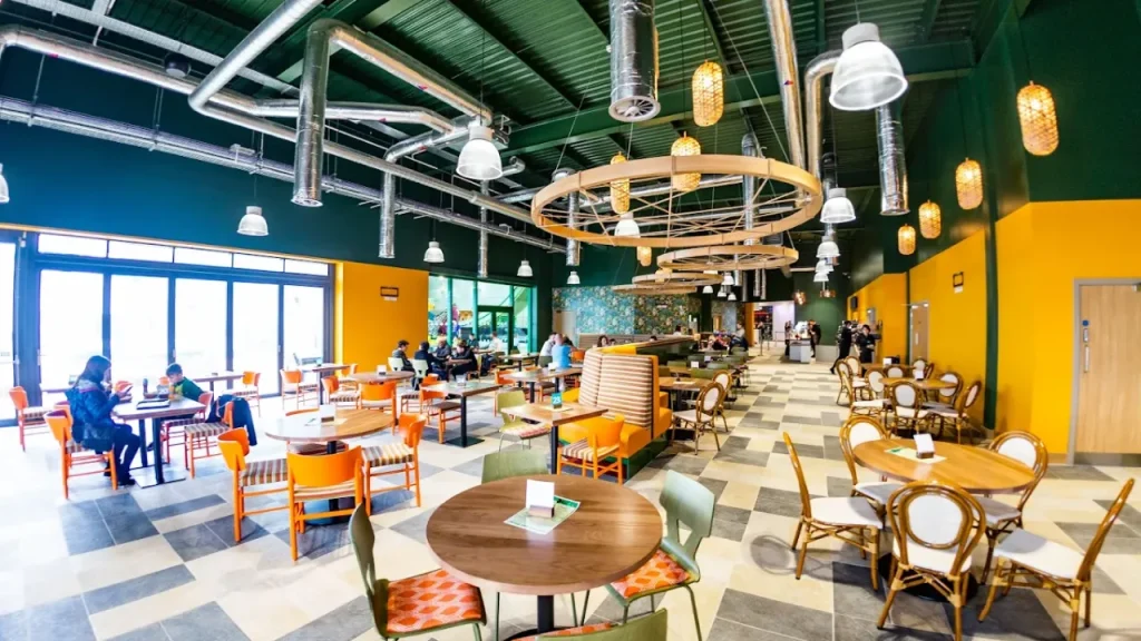 Modern indoor café at SC2 Rhyl featuring colourful furniture, overhead lighting, and guests enjoying food in a spacious, family-friendly setting.