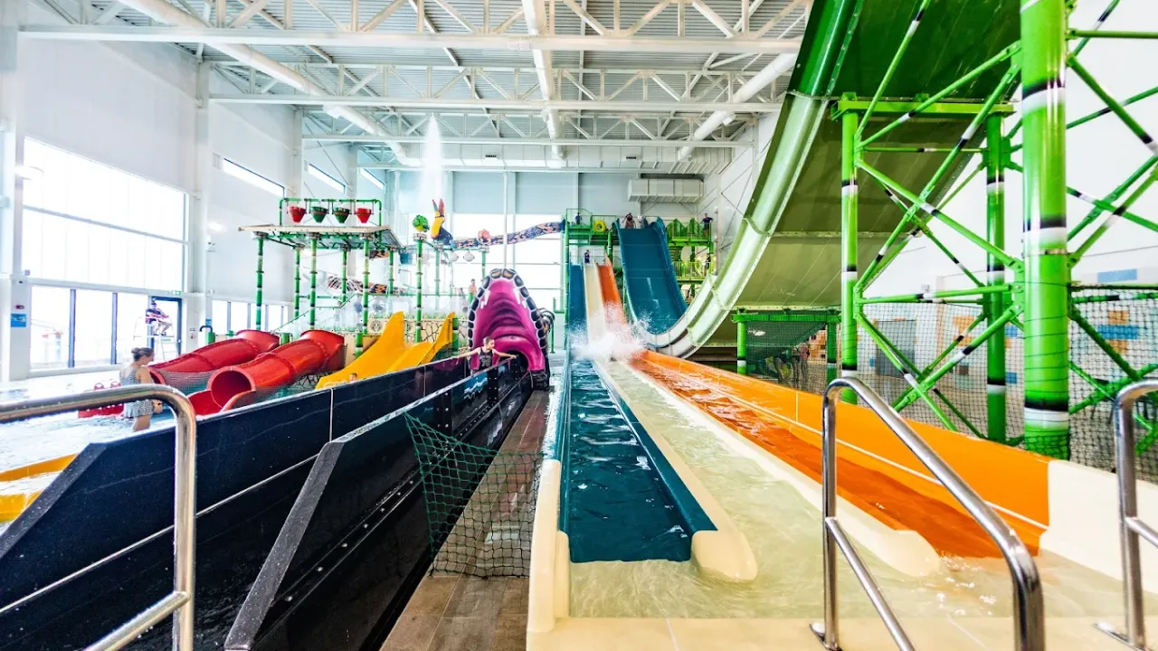 Indoor view of SC2 Rhyl’s racing water slides and play structures, with a splash landing in the flume zone and colourful slides in the background.