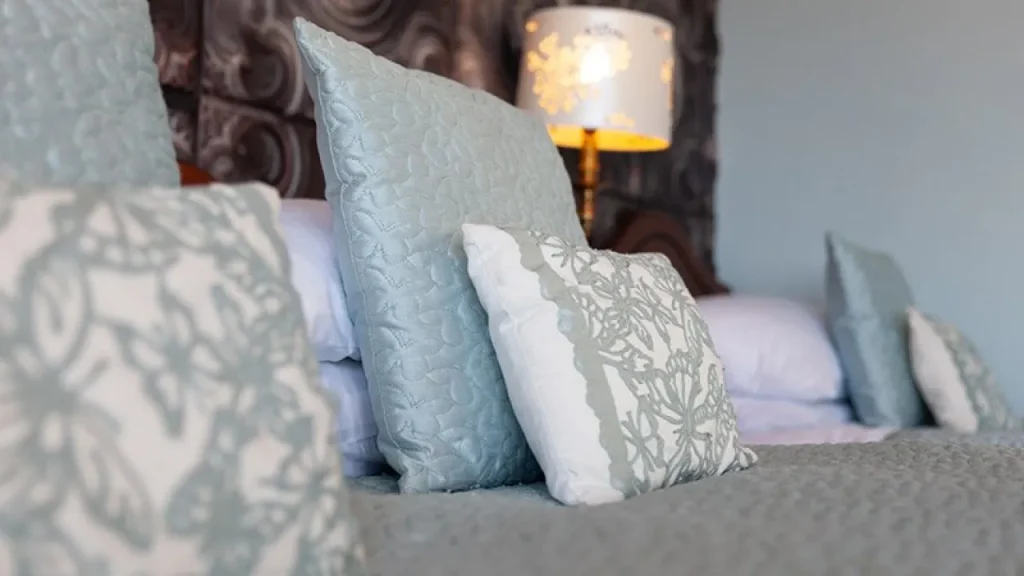 Close-up of decorative pillows on a neatly made bed with elegant textured fabrics at Shelleven Guest House Bangor Northern Ireland