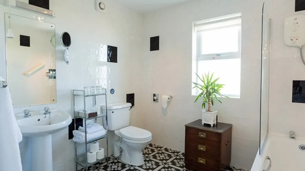 En-suite bathroom with pedestal sink, bath-shower, vintage floor tiles, and natural light at Shelleven Guest House Bangor Northern Ireland