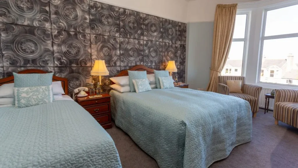 Family bedroom with double and single bed, vintage decor, patterned wall, and large bay windows at Shelleven Guest House Bangor Northern Ireland