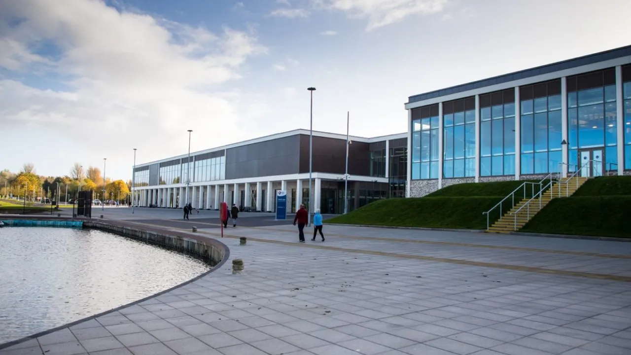 Wide lakeside view of South Lake Leisure Centre Craigavon with large glass windows and people walking outside