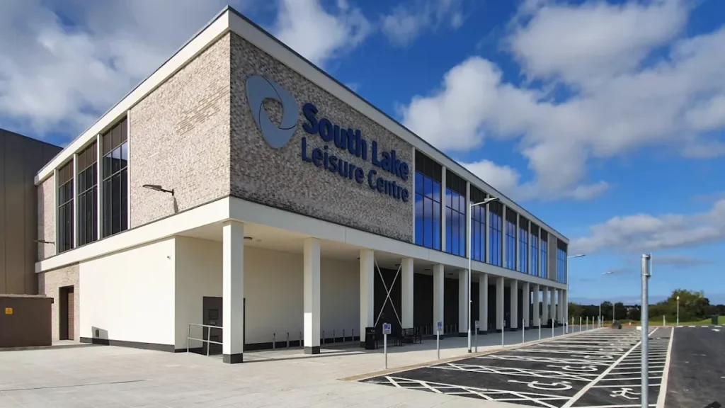 Front view of South Lake Leisure Centre Craigavon with accessible parking bays and glass-fronted building under blue sky