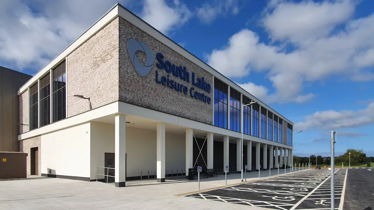 Front view of South Lake Leisure Centre Craigavon with accessible parking bays and glass-fronted building under blue sky